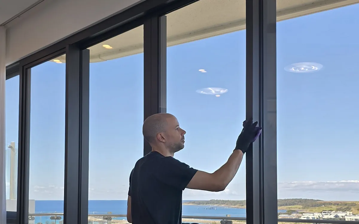 Clean Protocol cleaning floor-to-ceiling glass in a Shell Cove apartment